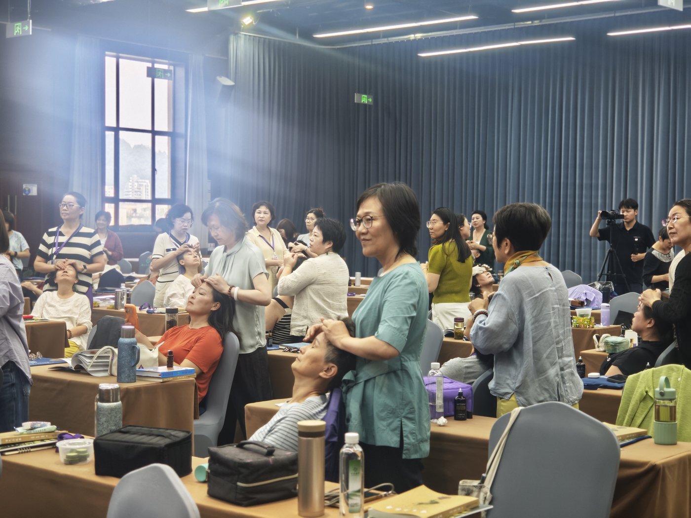 Students standing behind seated classmates, working on head and face pressure points