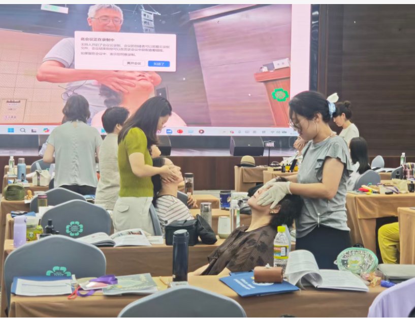 Students at classroom tables practicing techniques on each other with an anatomy diagram projected behind them